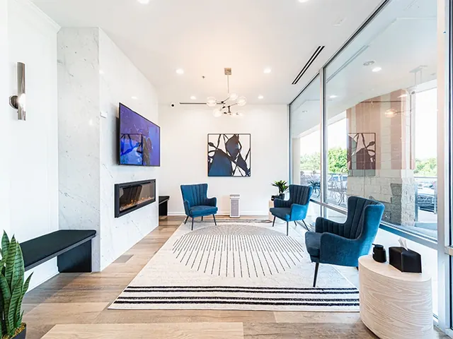 The bright waiting room, with blue armchairs, a fireplace and floor-to-ceiling windows.