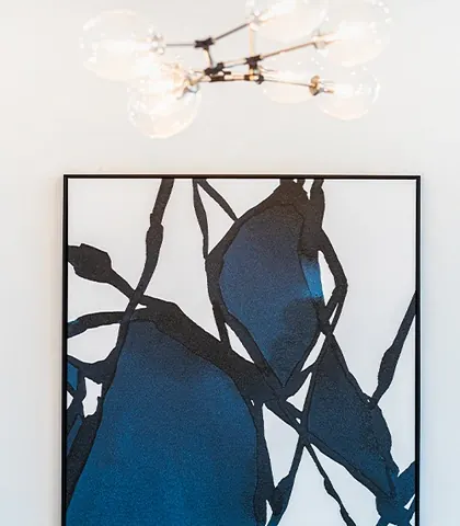 Blue abstract artwork under a globe chandelier.