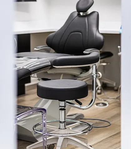 A black leather treatment chair and stool in one of the operatories.